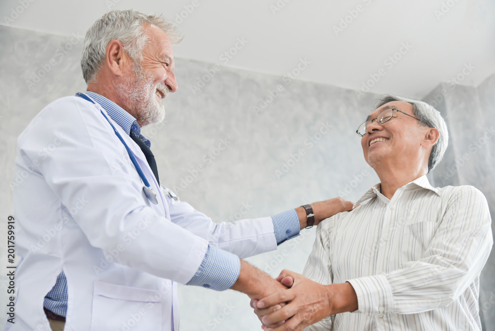 Senior male Doctor is handshaking to Asian male patient.
