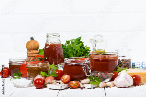 tomato sauces, pasta and fresh ingredients on white wooden table