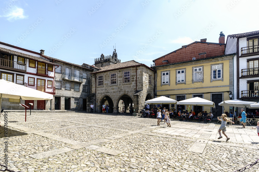 Downtown square of the village with cobblestone floor and stone facades of old houses with arches communicating with the Plaza del Salado and children playing in it