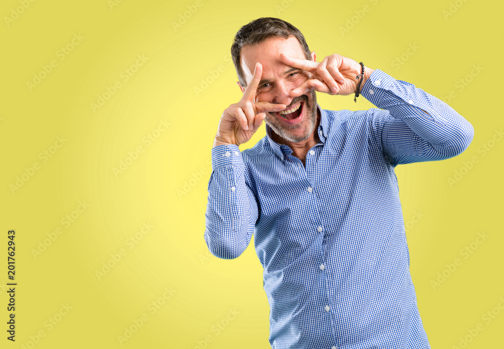 Handsome middle age man looking at camera through her fingers Handsome middle age man looking at camera through her fingers