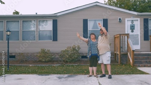 Heavy couple waving and saying goodbye to someone in front of their home
