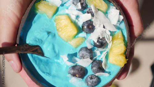 hands holding blue majik smoothie bowl approaching camera lens photo