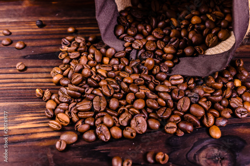 Roasted coffee beans in sack on wooden table
