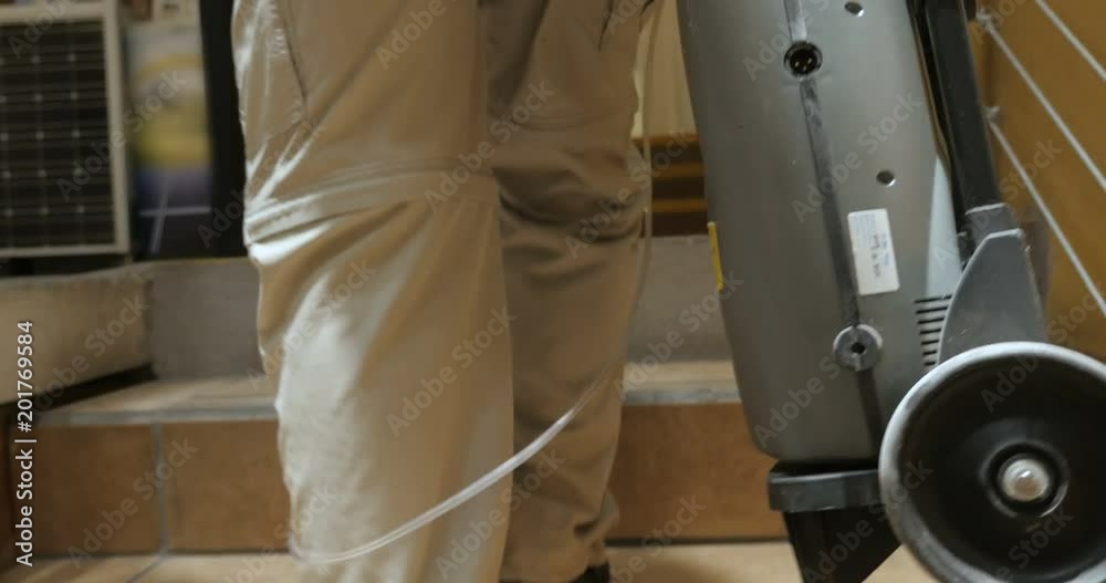 Elderly man carrying a portable oxygen tank with tubes up stairs in a market