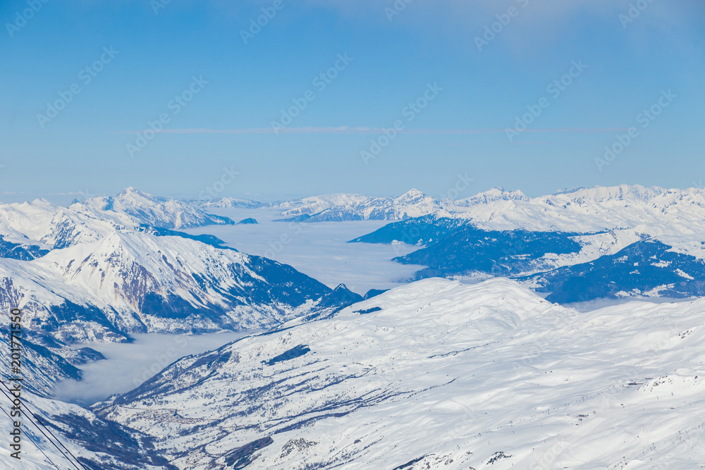 Aerial view to mountain valley with clouds at French alps. Mountain ski resort Three Valleys, France.
