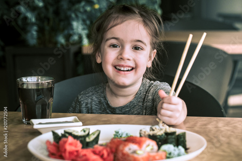 Little girl is eating sushi photo