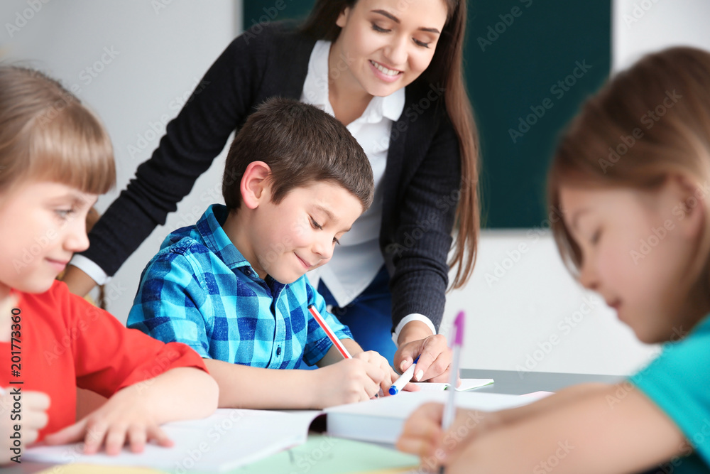 Female teacher helping boy with his task in classroom at school Female teacher helping boy with his task in classroom at school