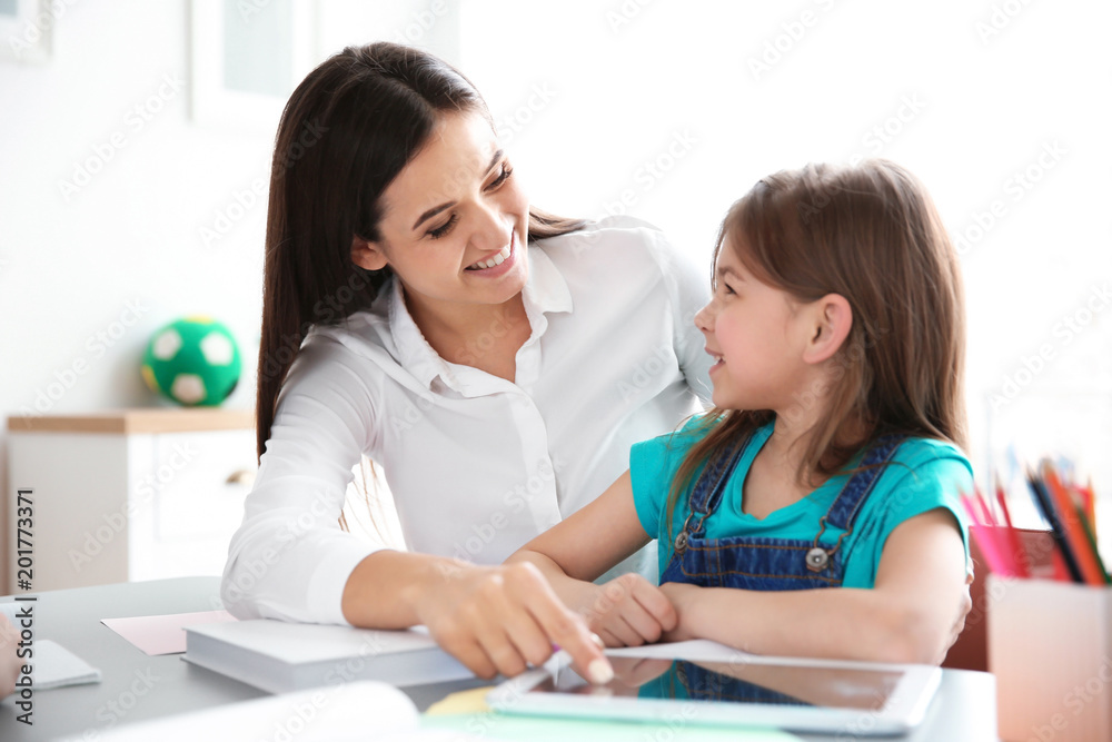 Female teacher helping girl with her task in classroom at school Female teacher helping girl with her task in classroom at school