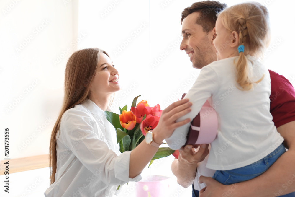 Happy woman receiving flowers and gift from her family at home. Mother's day celebration Happy woman receiving flowers and gift from her family at home. Mother's day celebration