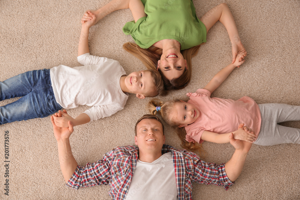 Happy family lying on cozy carpet at home, top view