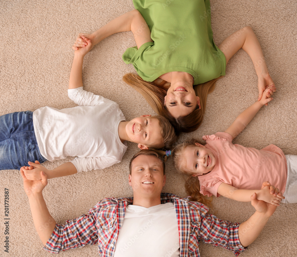 Happy family lying on cozy carpet at home, top view