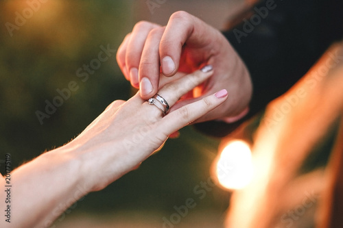 Wedding ceremony. The groom wears an engagement ring with a diamond on the bride's finger, close-up hands