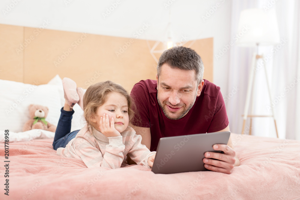 Relaxing. Inspired loving daddy spending time with his daughter and watching a film Relaxing. Inspired loving daddy spending time with his daughter and watching a film