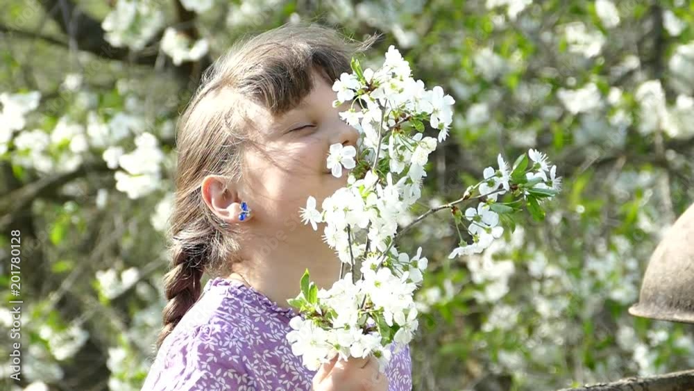 Young girl near beautiful flowering tree. Flowering garden in spring. Beautiful girl holding a branch and flowers in her hands. Young girl near beautiful flowering tree. Flowering garden in spring. Beautiful girl holding a branch and flowers in her hands.