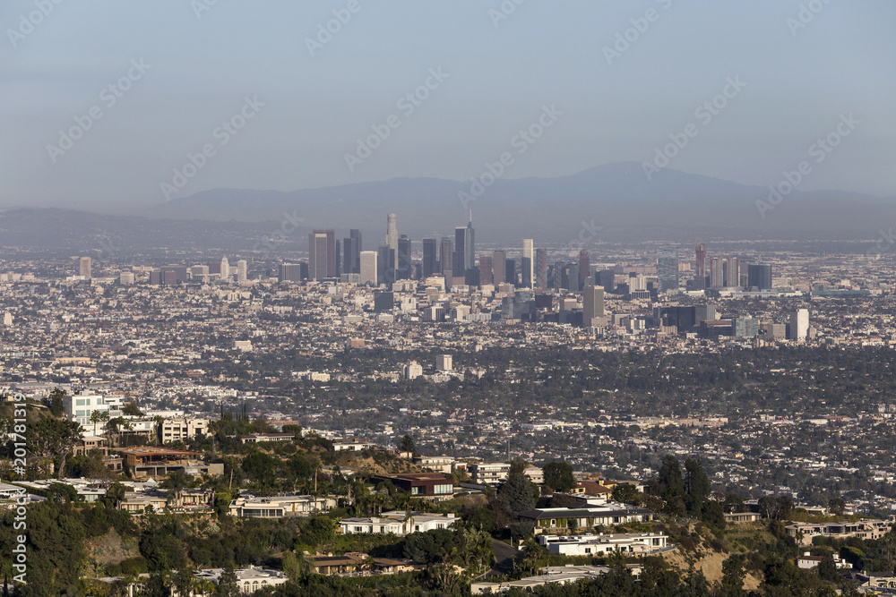 Aerial view of Hollywood Hills homes with smoggy downtown Los Angeles California in background.