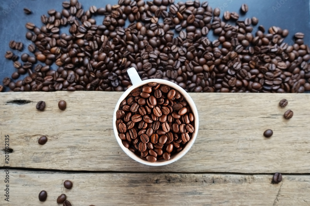 Roasted coffee beans texture with coffee beans scattered on dark background and white cup – top view
Roasted coffee beans texture with coffee beans scattered on dark background and white cup – top view