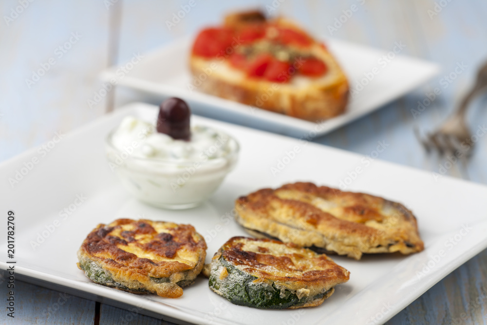 Gebackene Zucchini mit Tsaziki auf Teller Gebackene Zucchini mit Tsaziki auf Teller