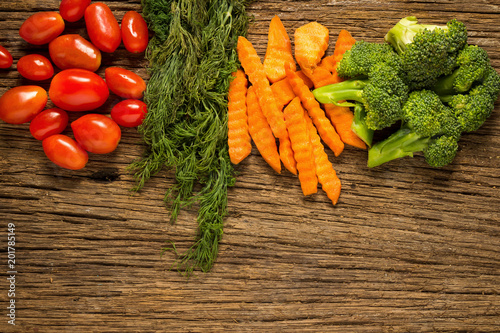 dill. baby tomatoes. carrot. broccoli. on wood textured. kitchen wood. table wood. background. space