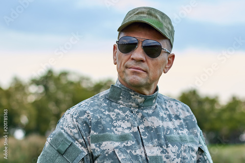 Sergeant in sunglasses. Severe serious cool soldier in spectacles and cap outdoors.