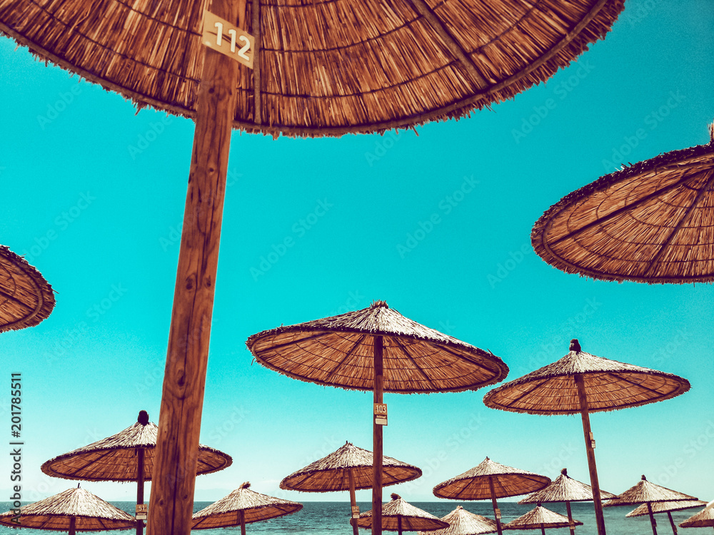 The beach umbrellas against the blue sky, sun parasols, thatched parasols, Kassandra, Greece. The beach umbrellas against the blue sky, sun parasols, thatched parasols, Kassandra, Greece.