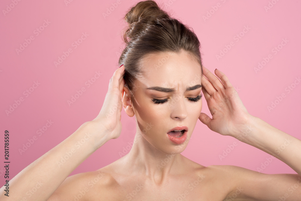 Hurt. Portrait of unhappy female is standing with closed eyes and touching her temples while suffering from pain. Isolated on pink background Hurt. Portrait of unhappy female is standing with closed eyes and touching her temples while suffering from pain. Isolated on pink background
