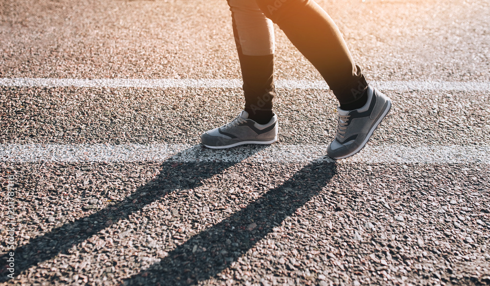 Fitness woman running on asphalt road at sunset. Close up. White line. Fitness woman running on asphalt road at sunset. Close up. White line.