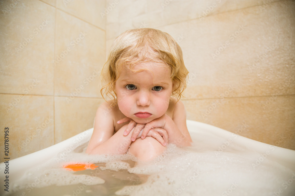 Little cute baby is upset and sits in the bathroom