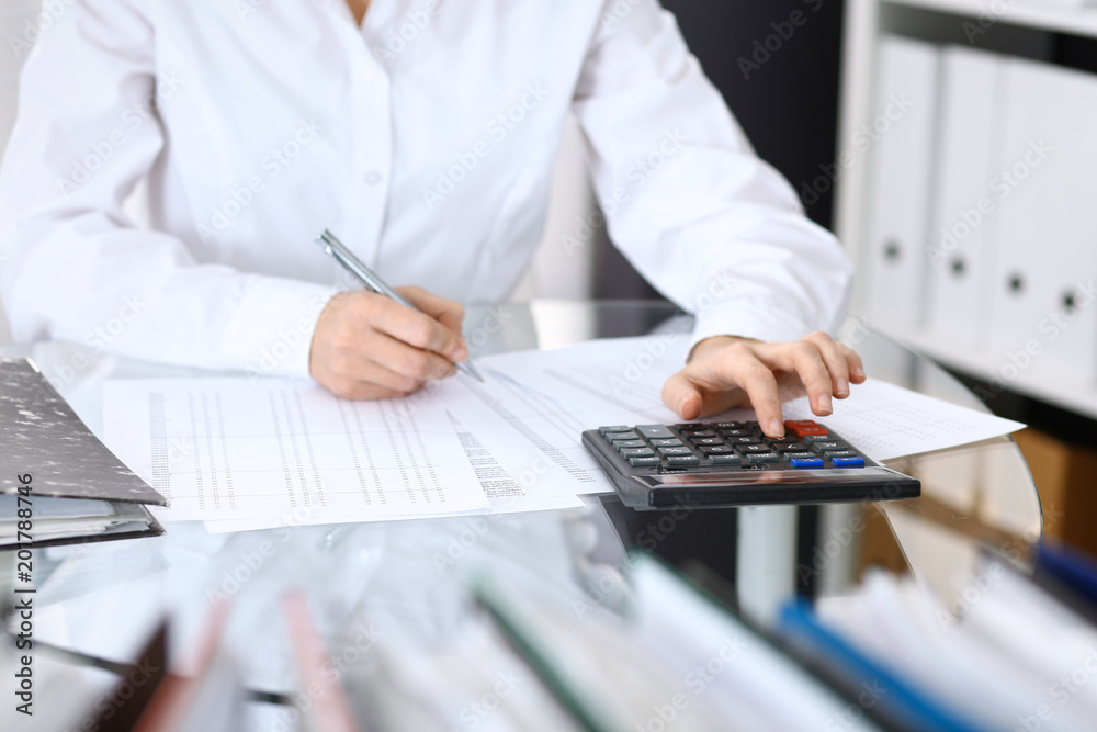Female bookkeeper or financial inspector making report, calculating or checking balance. Internal Revenue Service checking financial document. Audit concept in business Female bookkeeper or financial inspector making report, calculating or checking balance. Internal Revenue Service checking financial document. Audit concept in business