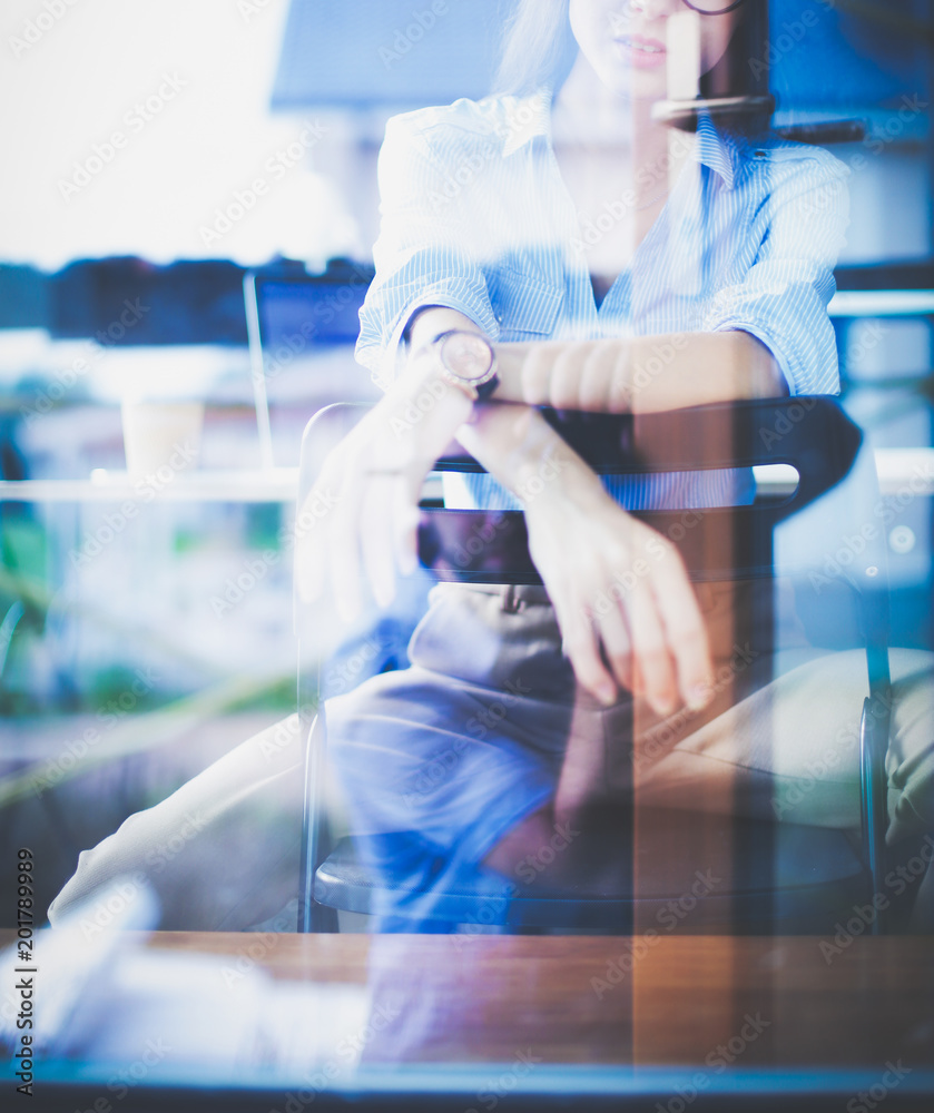 Young woman sitting at office table with laptop,view through window. Young woman Young woman sitting at office table with laptop,view through window. Young woman