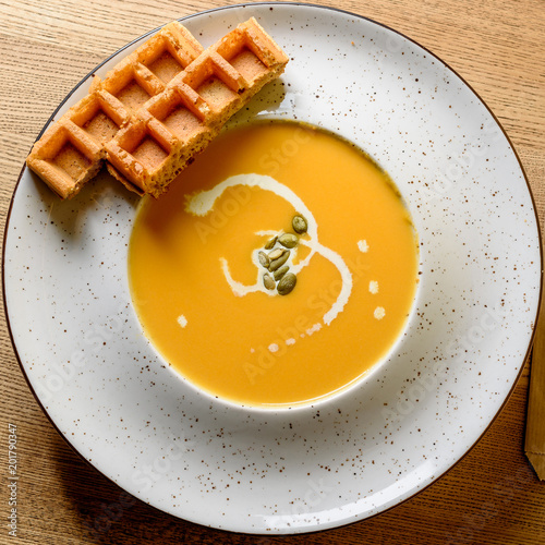 Hot pumpkin soup in white bowl with Belgian waffles. View from above, macro view photo