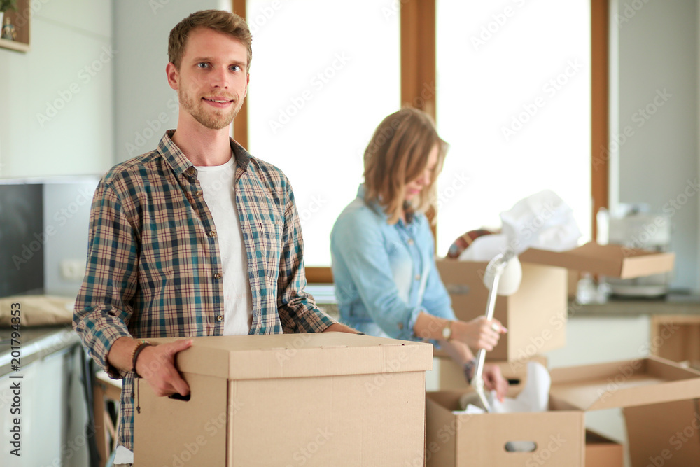 Couple unpacking cardboard boxes in their new home. Young couple. Couple unpacking cardboard boxes in their new home. Young couple.