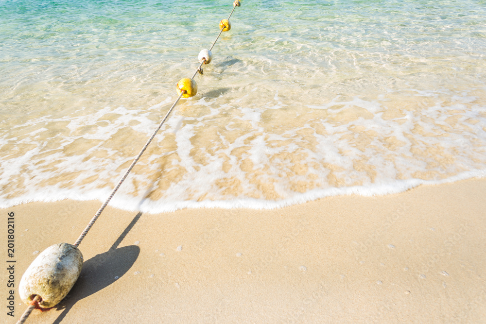 Obraz premium Buoys on the blue beach and soft waves with foam background