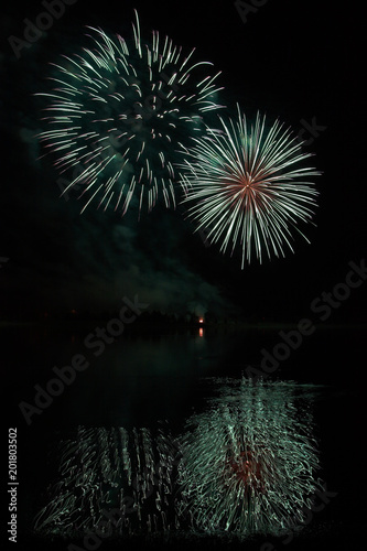 Fireworks of many colors on  display and refelcting in a lake photo