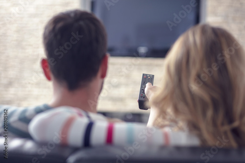 Happy young couple relaxing and watching TV at home. photo