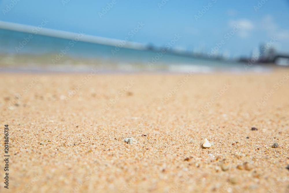 Fototapeta premium Focus of the sand on the beach with blur background of blue sea