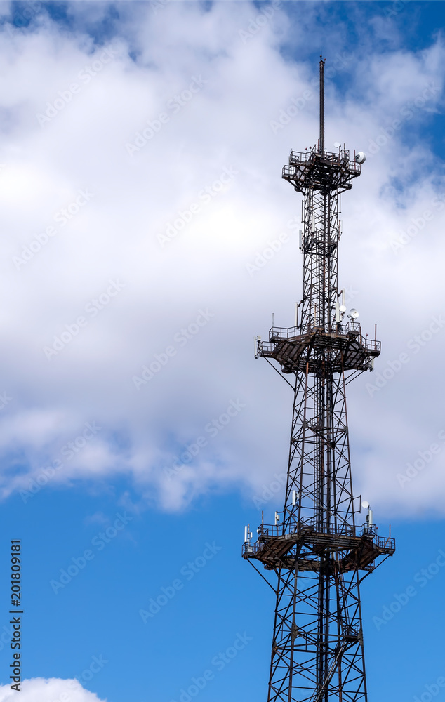 telecommunication tower with a parabolic antennas on a background of blue sky and clouds telecommunication tower with a parabolic antennas on a background of blue sky and clouds