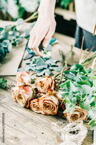 Florist at work on arragment flower bouquet on a wooden table photo