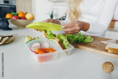 Mother preparing school lunch for childrens in home kitchen