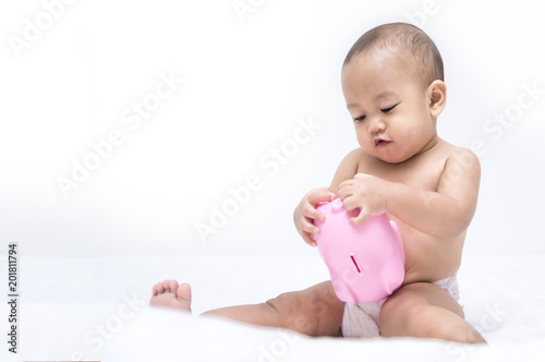 Baby happy with pink piggy bank on white bed, Money saving for education