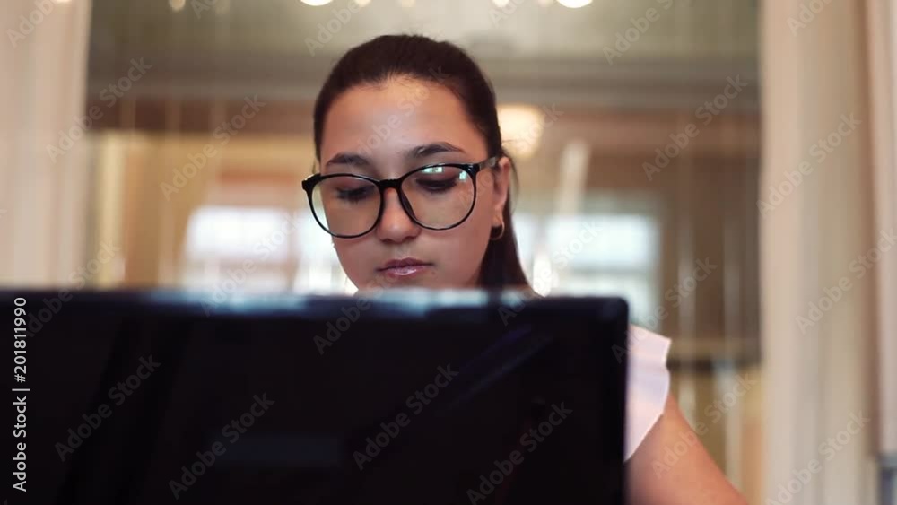 Business woman in glasses works using computer sitting at table in office. Close-up. Business woman in glasses works using computer sitting at table in office. Close-up.