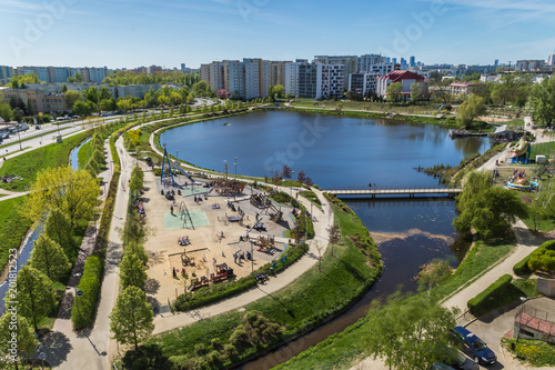 Leisure time at the Lake Balaton in the Goclaw residential district in Warsaw on a sunny day. People spending time playing at the children playground surrounded by the nature, green trees, blue water