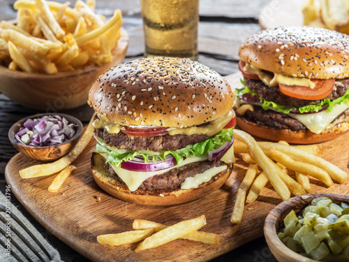 Hamburgers and French fries on the wooden tray.