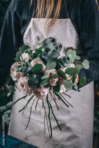 Florist at work on arragment flower bouquet on a wooden table photo