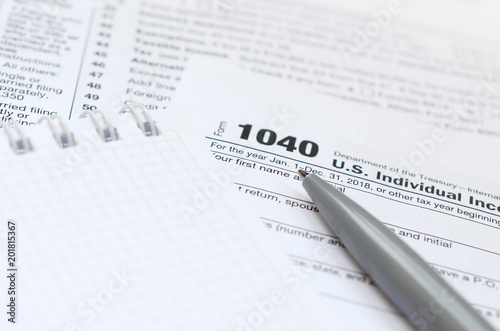 The pen and notebook is lies on the tax form 1040 U.S. Individual Income Tax Return. The time to pay taxes photo