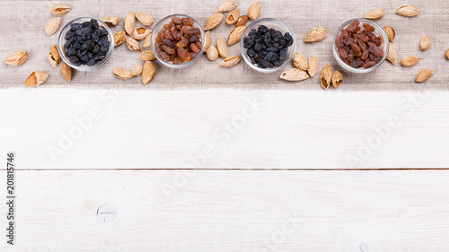 Organic food amonds, raisins in wooden bowl. Food mix background, top view, flat lay, copy space, banner.