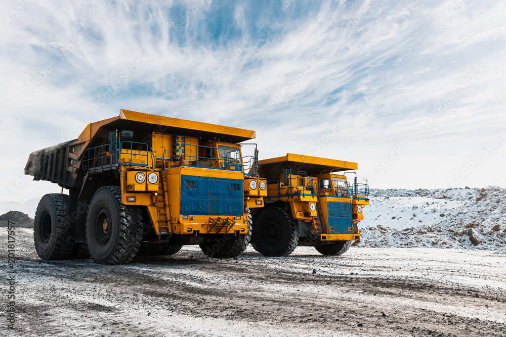 Obraz premium Large quarry dump truck. Loading the rock in dumper. Loading coal into body truck. Production useful minerals. Mining truck mining machinery, to transport coal from open-pit as the Coal Production.