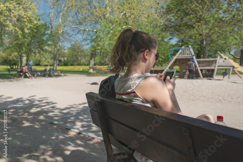 Cute Girl with mobile texting on a park bank © Tom Baur