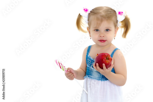 A little girl licks a candy on a stick.