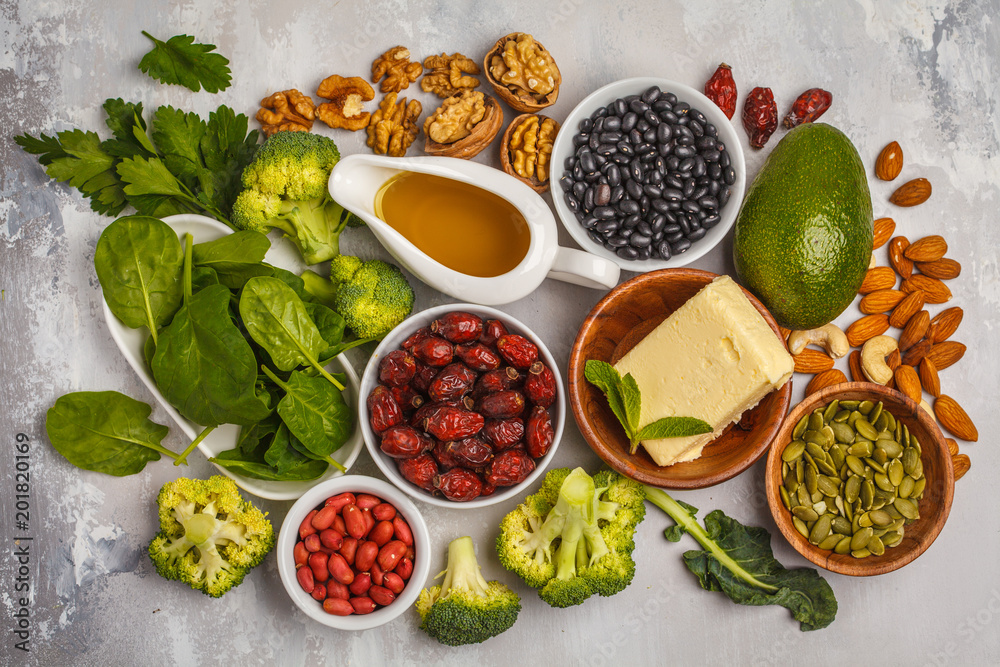 Fototapeta Healthy food nutrition dieting concept. Assortment of high vitamin E sources. Oil, nuts, avocado, butter, healthy fats, rose hips, parsley, seeds, spinach. White backgdound, top view