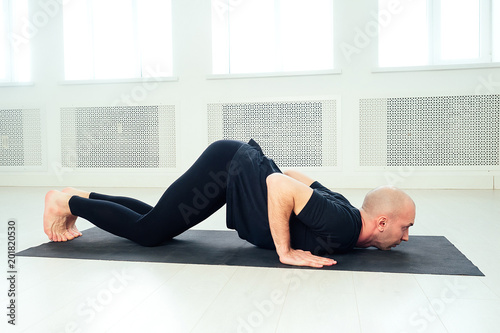 the man is practicing yoga in the studio. morning asanas in yoga class